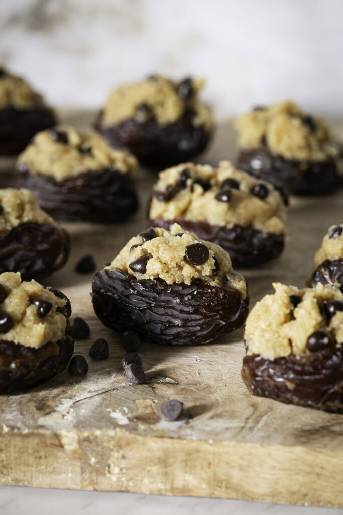cookie dough stuffed dates on a wooden cutting board.