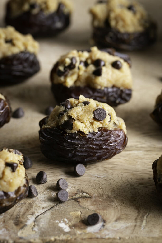 cookie dough stuffed dates on a wooden cutting board.