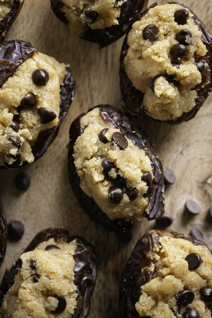 close up overhead shot of cookie dough stuffed dates on a wooden cutting board.
