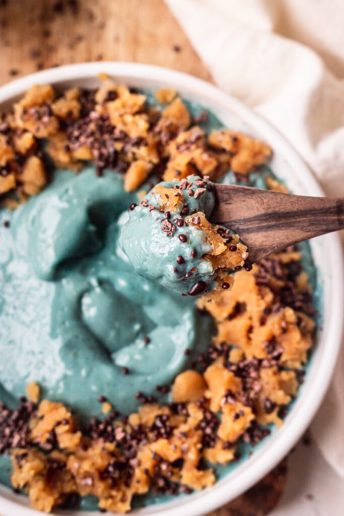 a close up of a spoonful of smoothie bowl with the smoothie bowl blurred in the background.