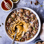 a pumpkin pie smoothie in a bowl topped with cookie dough balls, pumpkin seeds, pecans, chocolate covered chia seeds drizzled with maple syrup