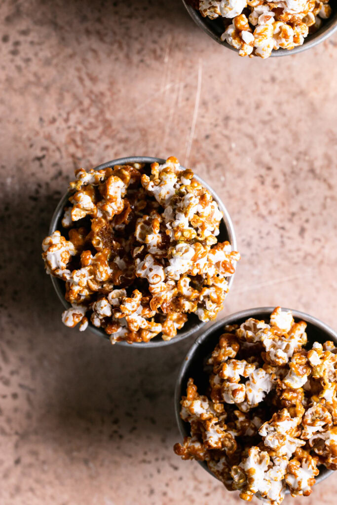 an overhead shot of two buckets of popcorn and one in the corner peeking in
