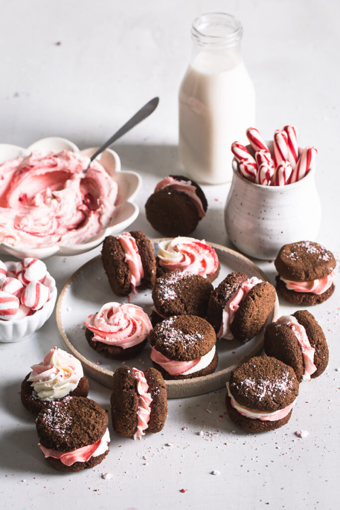a cookie set up with peppermint candies, jug of milk, and a bowl of peppermint cream filling