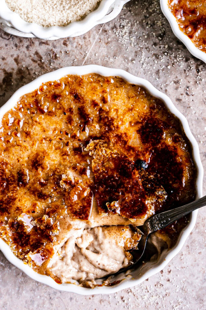 close up of a vegan gingerbread creme brûlée with a spoon scooping some out