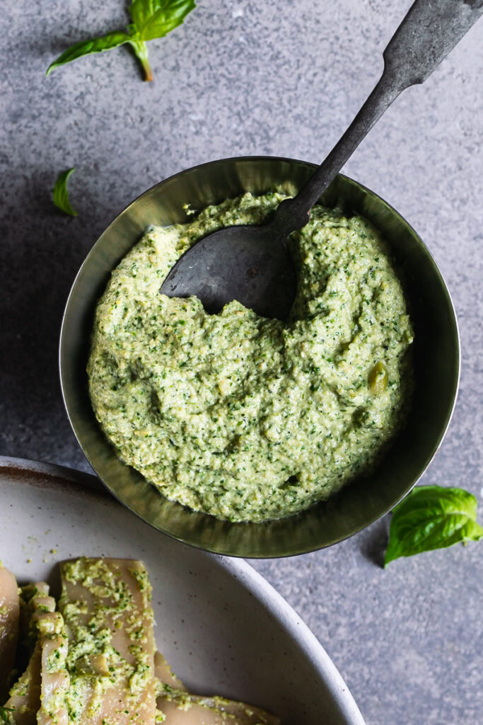 a bowl of olive pesto with a spoon in it