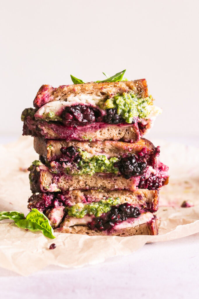 vertical image of vegan blackberry pesto grilled cheese sandwich stacked on top of one another