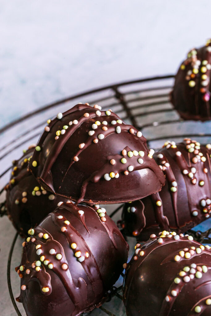 a vertical close up image of chocolate eggs decorated with sprinkles