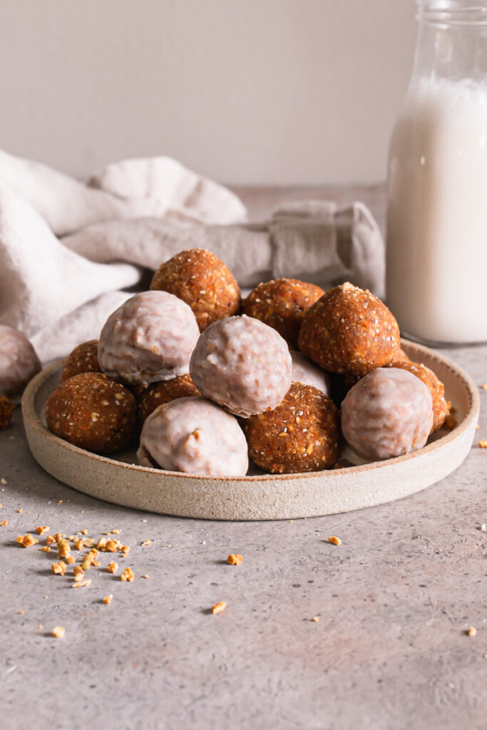 a head on shot of no-bake carrot cake granola bites with a jar of milk in the background