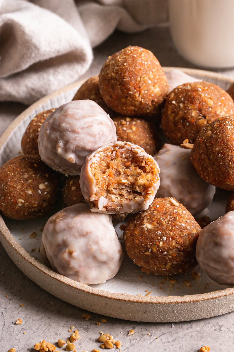 a bowl of carrot cake granola bites with one of them taken a bite out of it