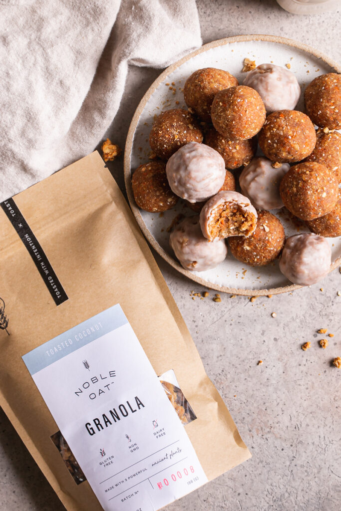 a bowl full of no-bake carrot cake granola bites with a bag of noble oat toasted coconut granola next to it