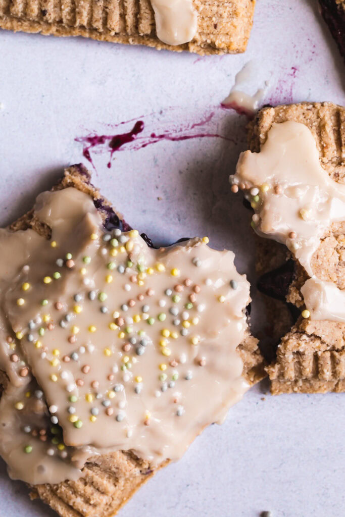 a close up of one pop tart broken apart with blueberry filling smeared on the backdrop