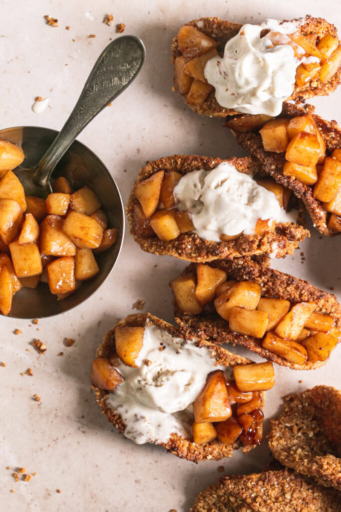 close up of apple pie tacos with partially melted ice cream and a bowl of apple pie filling on the side