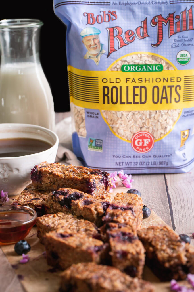head on view of Blueberry Oatmeal French Toast Sticks piled on top of one another with a bag of Bob's Red Mill Organic Old Fashioned Rolled Oats in the background
