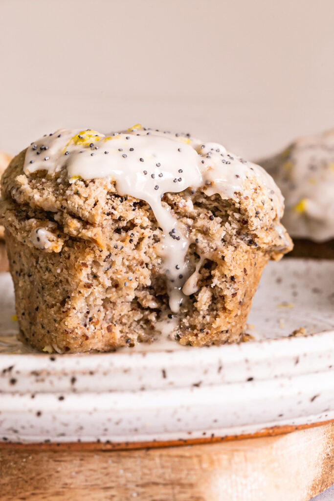 a close up of a lemon poppy seed muffin glazed with icing and a bite taken out of it