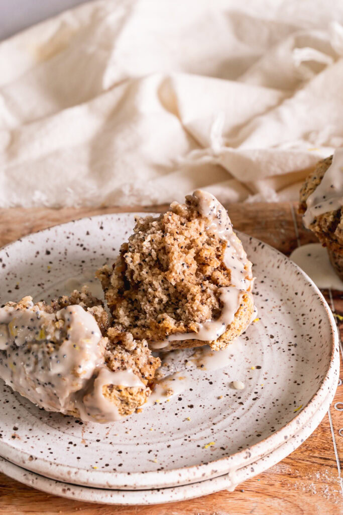 a lemon poppy seed muffin broken in half on a plate