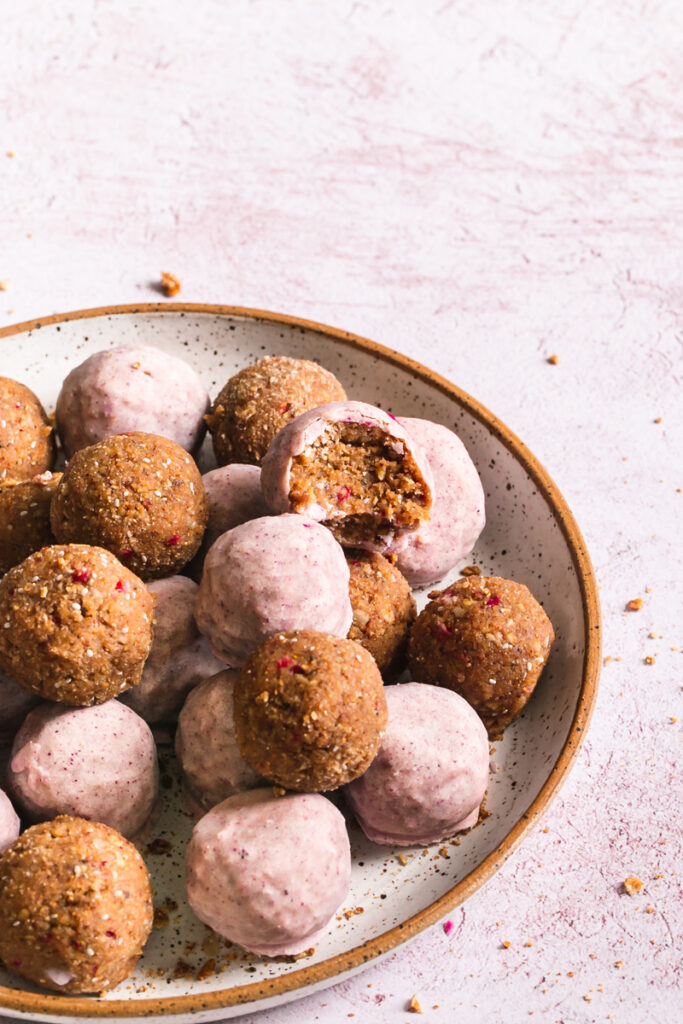 side view of strawberries and cream granola bites one with a bite taken out of it