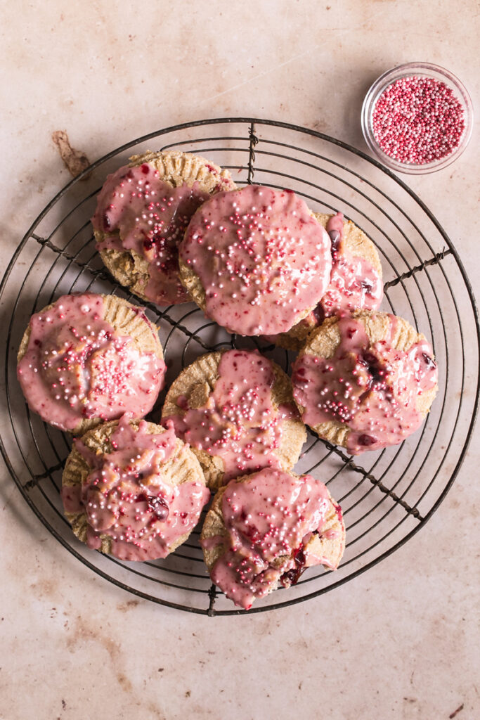 round wire cooling rack with round cherry pop tarts overlapping on top and a bowl of pink sprinkles beside it