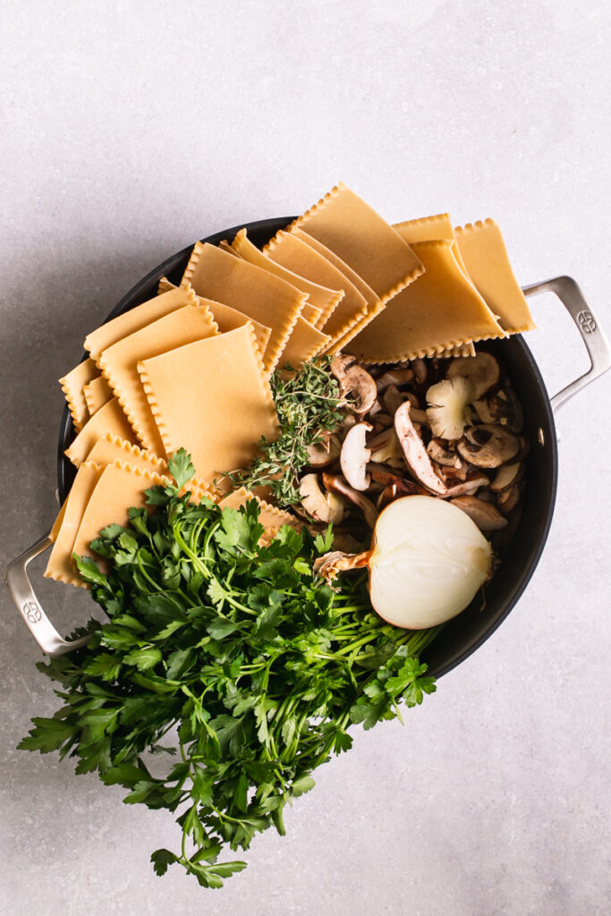 Calphalon Calphalon Premier™ Hard-Anodized Nonstick dutch oven with uncooked lasagna noodles, parsley, onion, mushrooms in it