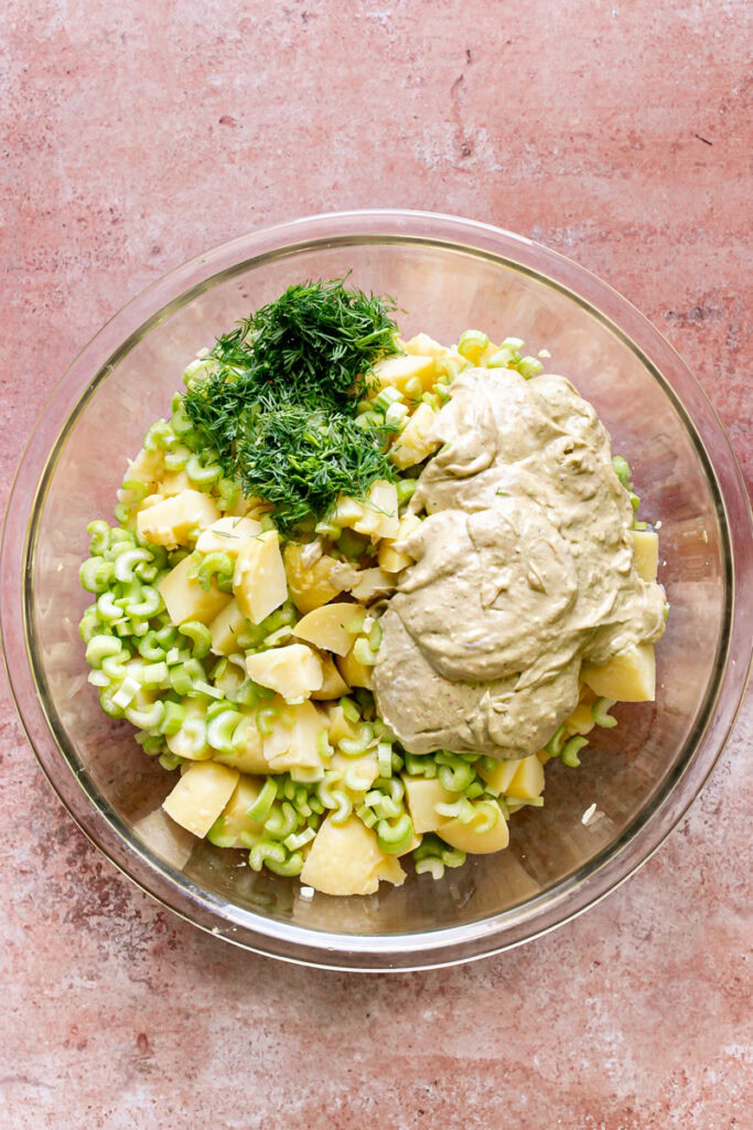 cooked potatoes, sliced celery, chopped dill, and smoked paprika dressing ingredients in a bowl