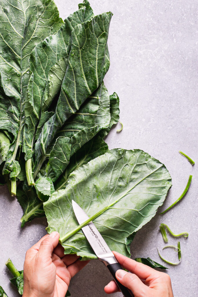 action shot of trimming the stem off the back of a collard green with a Calphalon knife