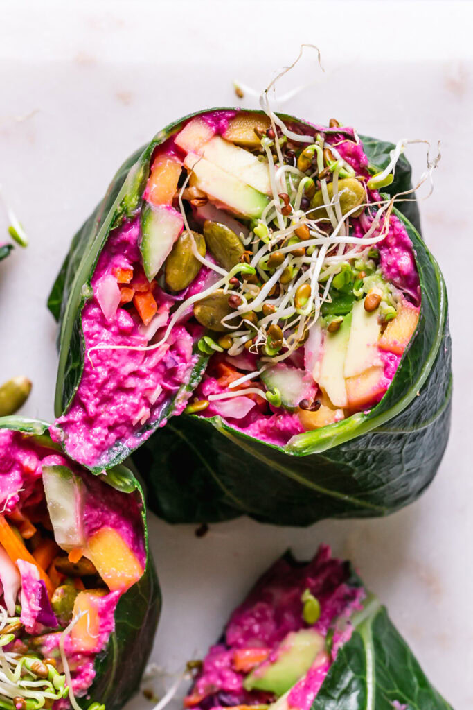 close up of beet hummus veggie collard wraps cut in half