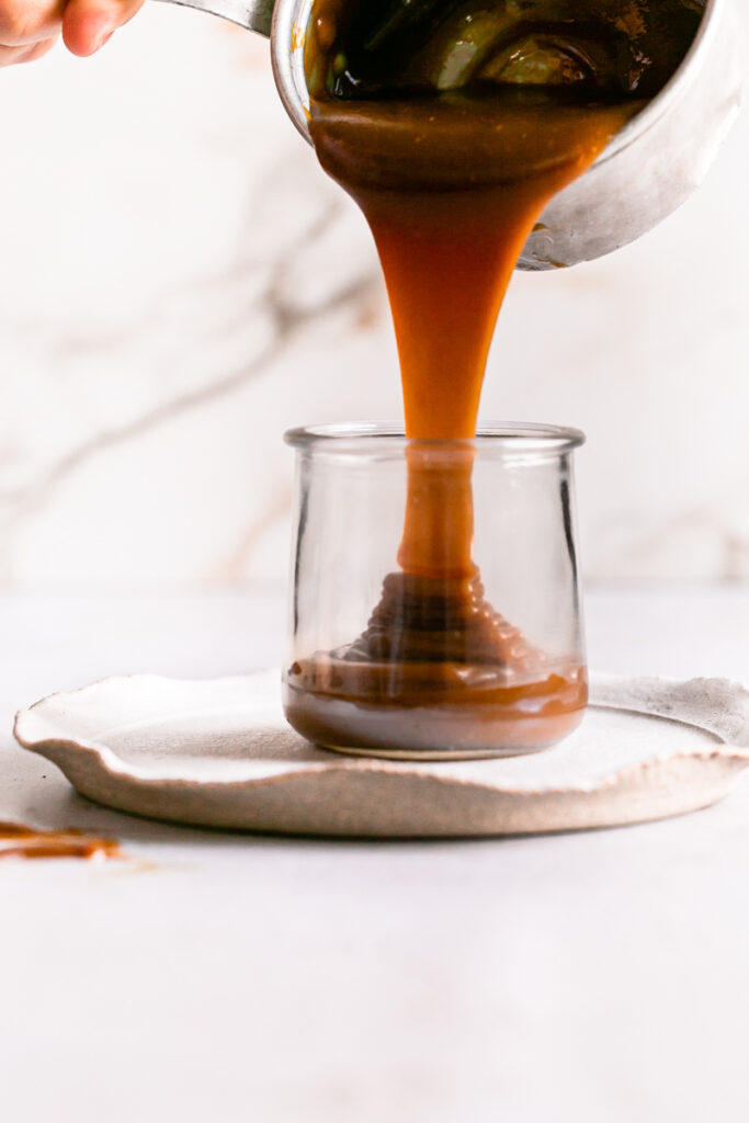 action shot of pouring the caramel from the saucepan into a jar