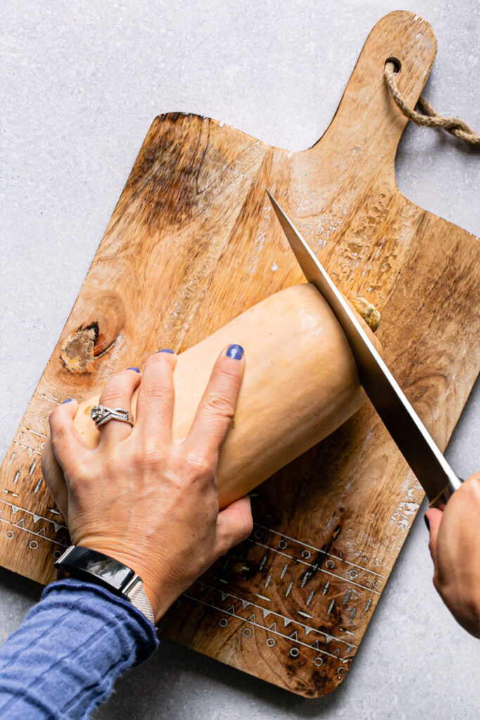 a photo of cutting the stem off of a butternut squash