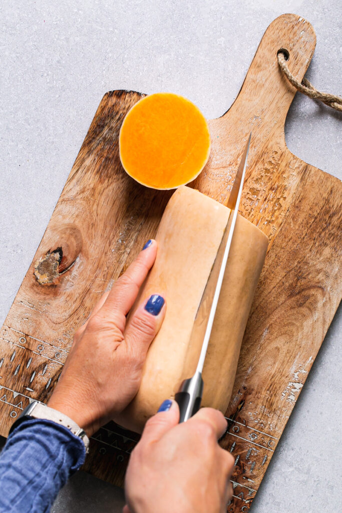 an action photo of slicing a butternut squash in half