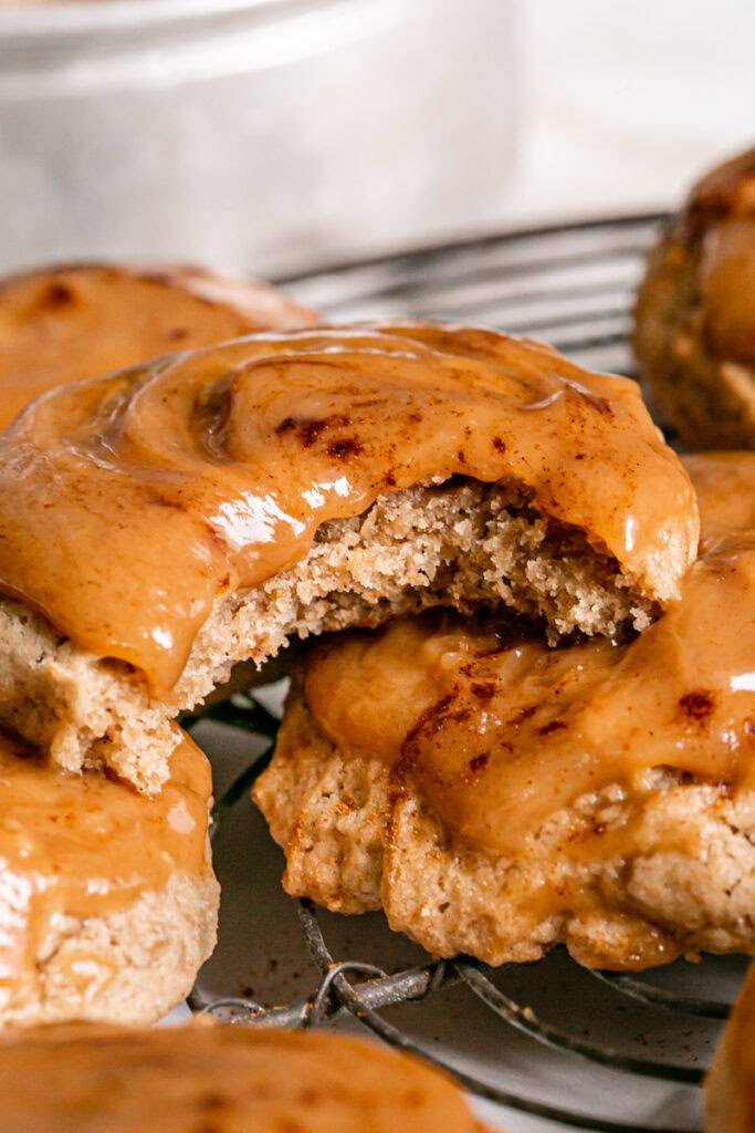 close up vertical shot of caramel apple cider cookies, one with a bite taken out of it