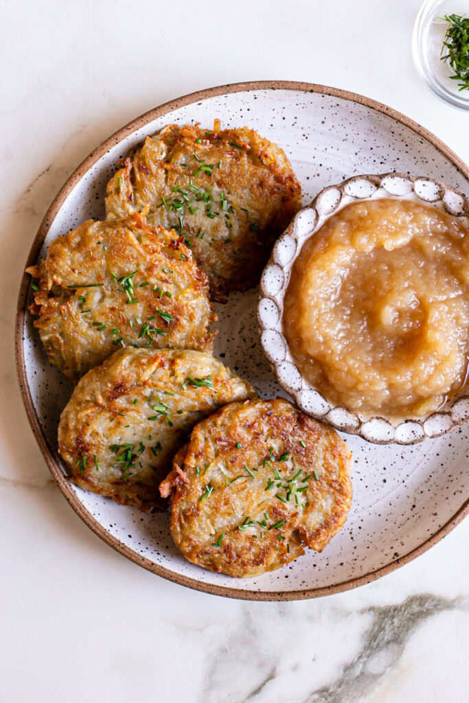 an overhead shot of four Gluten-Free Vegan Potato Pancakes on a plate with a side of applesauce