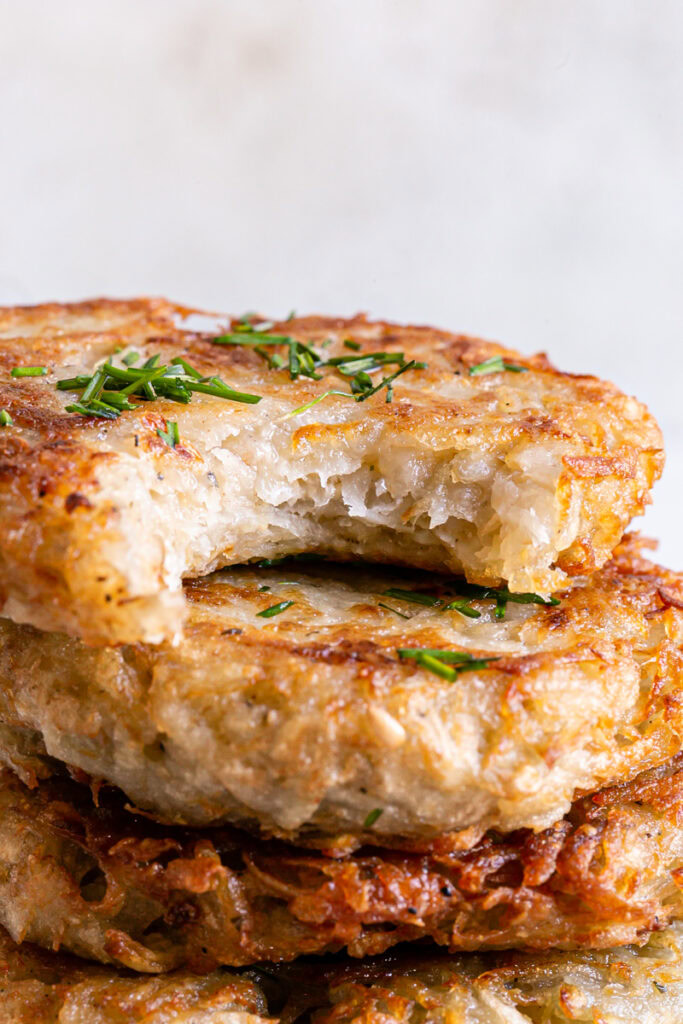 close up of potato pancakes stacked up the top one with a bite taken out of it