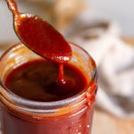 a close up 3/4 shot of bbq sauce dripping off a spoon