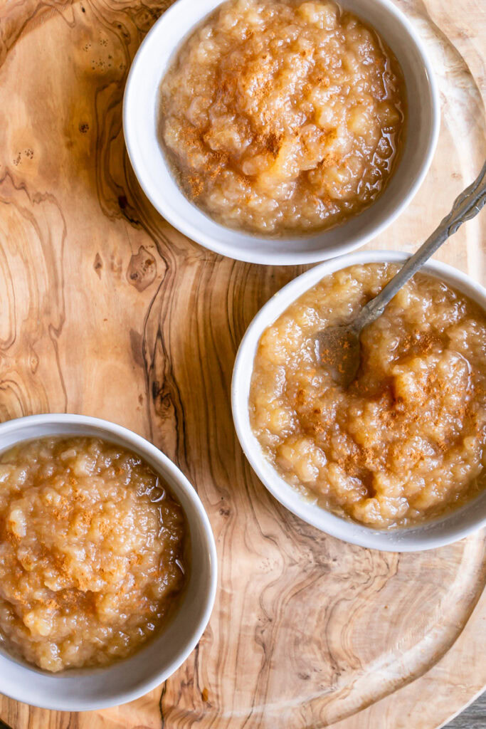 flatlay image of three bowls of Golden Delicious Applesauce on a wooden cutting board