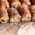 Pumpkin Cream Cheese Rollups lined up in a baking sheet lined with parchment paper