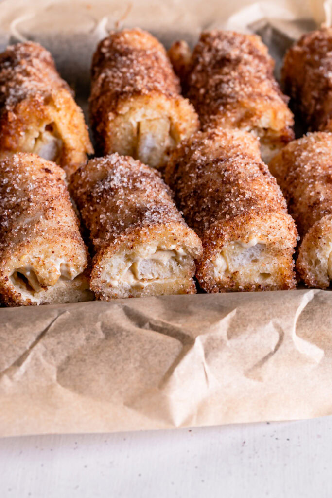 Pumpkin Cream Cheese Rollups lined up in a baking sheet lined with parchment paper