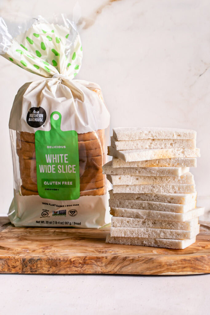 A loaf of little northern bakehouse bread in the bag with a stack of bread slices with the crusts cut off next to it