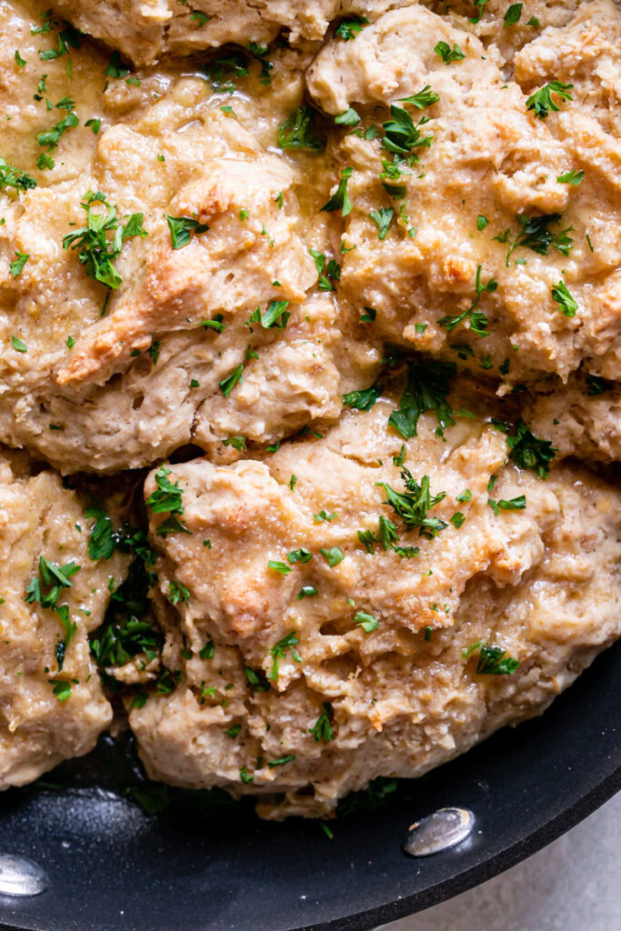 close up of Vegan Gluten-Free Buttermilk Skillet Biscuits in the skillet garnished with fresh parsley