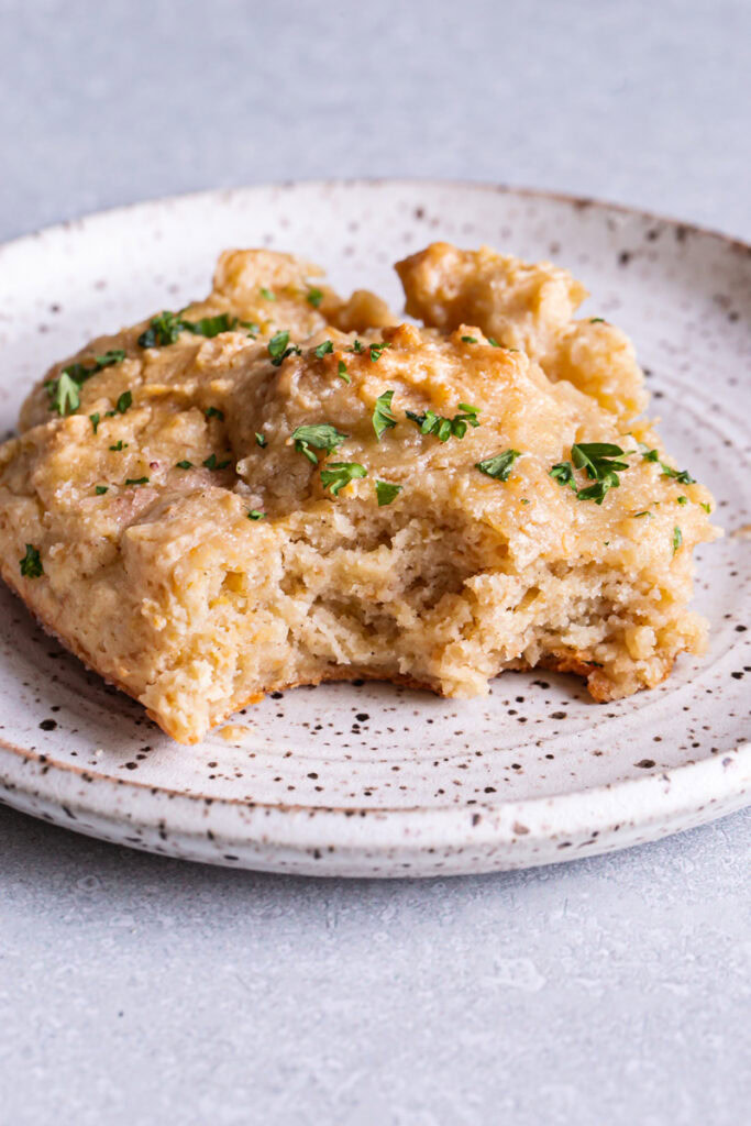 a single Vegan Gluten-Free Buttermilk Skillet Biscuits in the skillet garnished with fresh parsley served on a plate