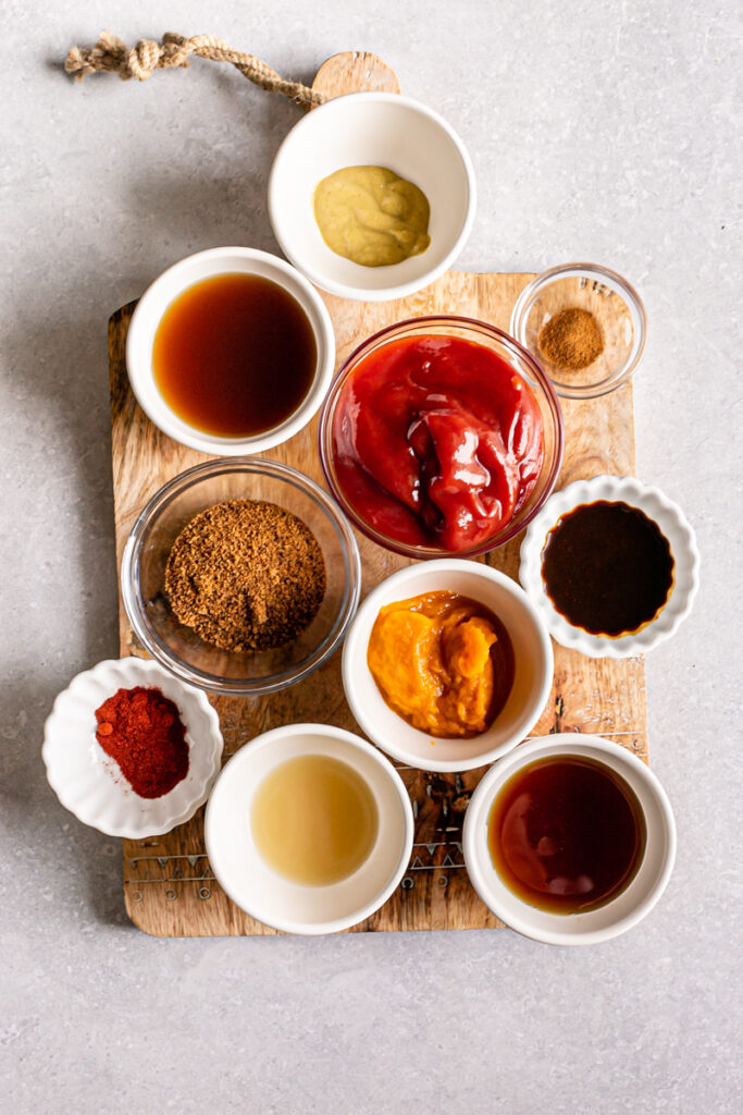 all of the Gluten-free Vegan Pumpkin BBQ Sauce ingredients measured out into bowls on top of a wooden cutting board