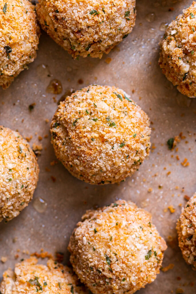 a close up of baked mashed potato croquettes on a baking sheet lined with parchment paper