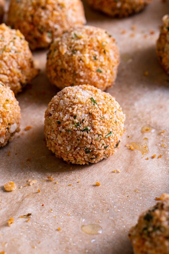 3/4 close up of baked mashed potato croquettes on a baking sheet lined with parchment paper