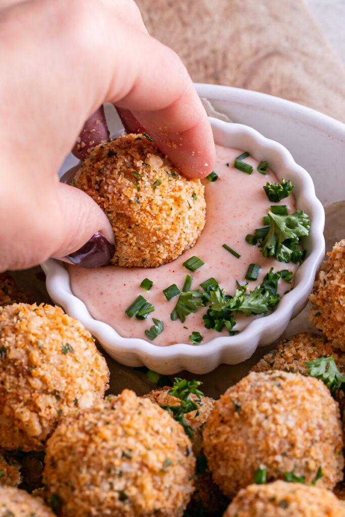 action shot dipping a mashed potato croquette into the dipping sauce
