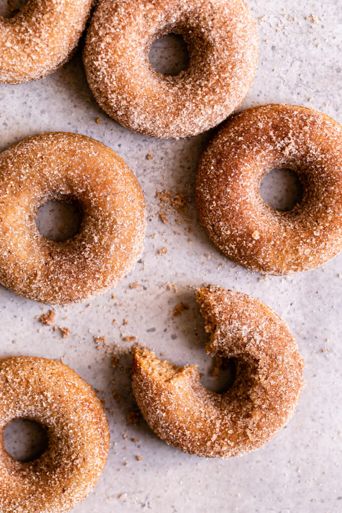 flat lay of cinnamon sugar donuts one with a bite taken out of it