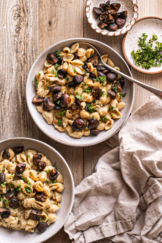 two bows of Creamy Alfredo Style Mushroom Pasta and a linen napkin in the lower right corner