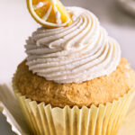 a close up of a frosted grain-free lemon cupcake with a candy lemon wedge on top.