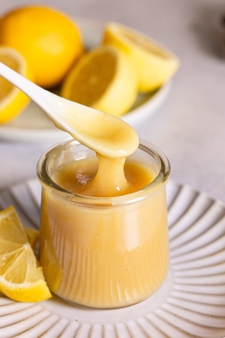 action shot of spooning some lemon curd out of the jar