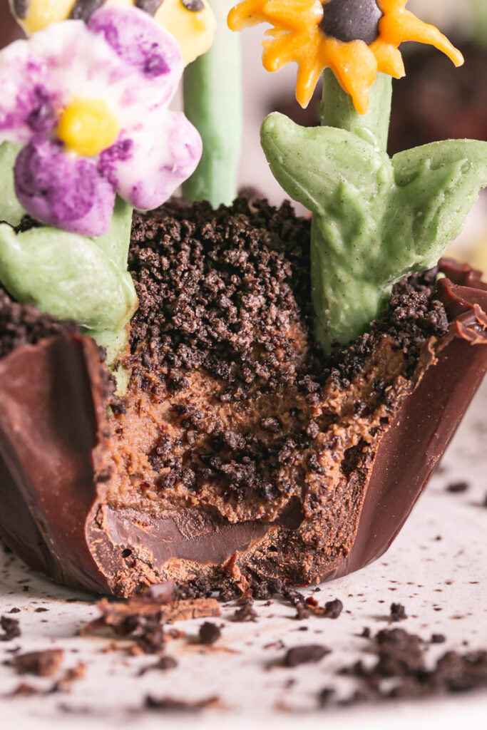 a very close up shot of a a close up of a Chocolate Avocado Pudding Dirt Cup with a bite taken out of it to show the chocolate avocado pudding filling