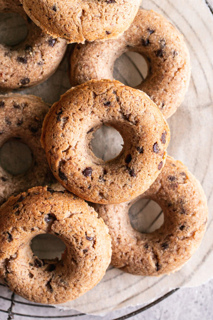 grain-free banana bread donuts piled on a round wire cooling rack.