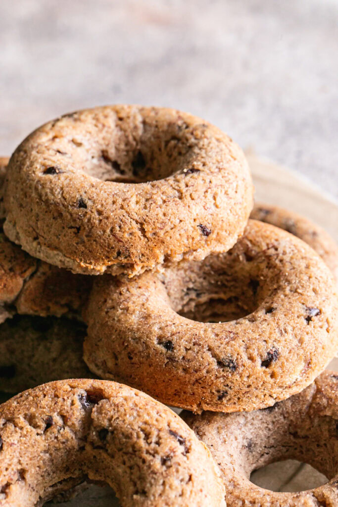 vertical image of grain-free banana bread donuts piled on a round wire cooling rack.