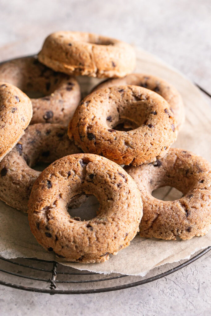 grain-free banana bread donuts piled on a round wire cooling rack.